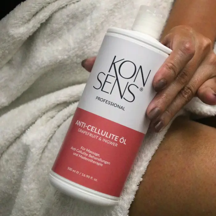 Grosse Flasche KONSENS Anti-Cellulite Öl (500 ml) wird in der Hand gehalten, bereit zur Anwendung bei Anti-Cellulite-Massage oder Maderotherapie – erhältlich bei Mel’s Beauty & Academy.